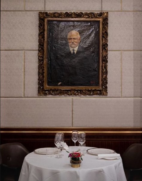 Tavolo apparecchiato sotto un ritratto d'epoca in una sala di Giannino dal 1899